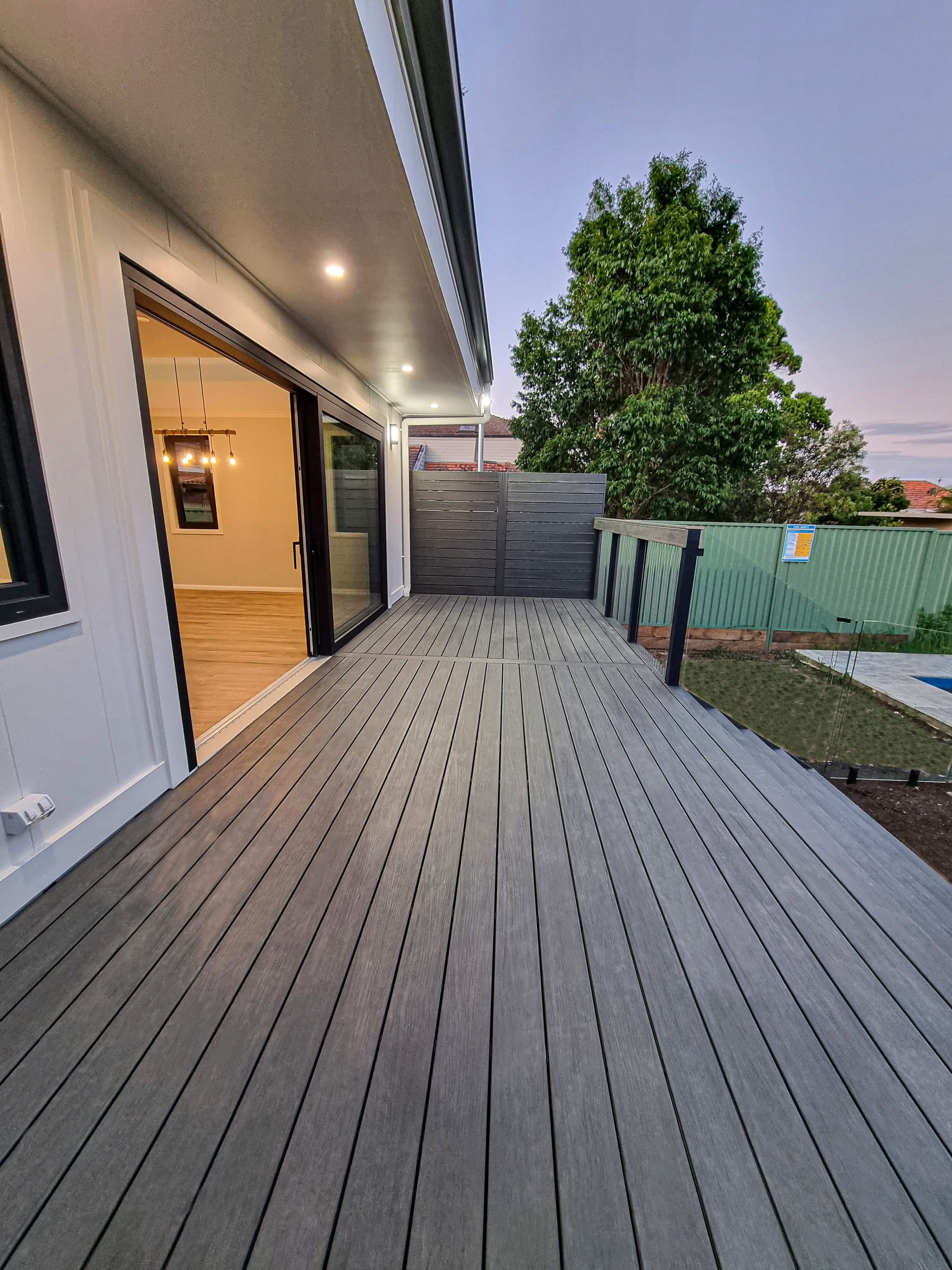 Composite timber deck running along the rear of the home to the pool and garden