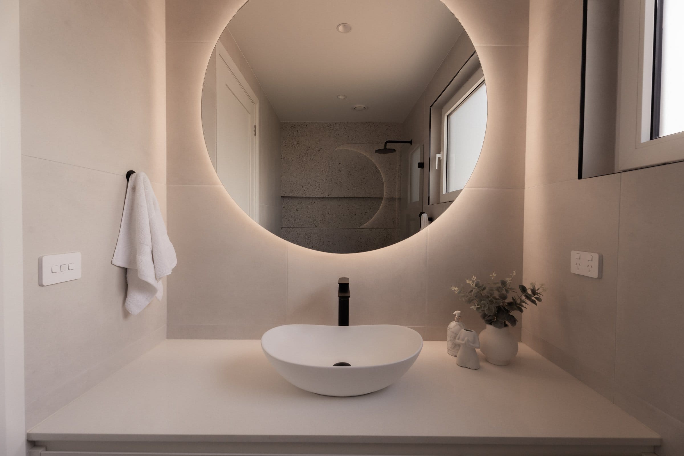 Ensuite with a vessel basin and backlit round mirror