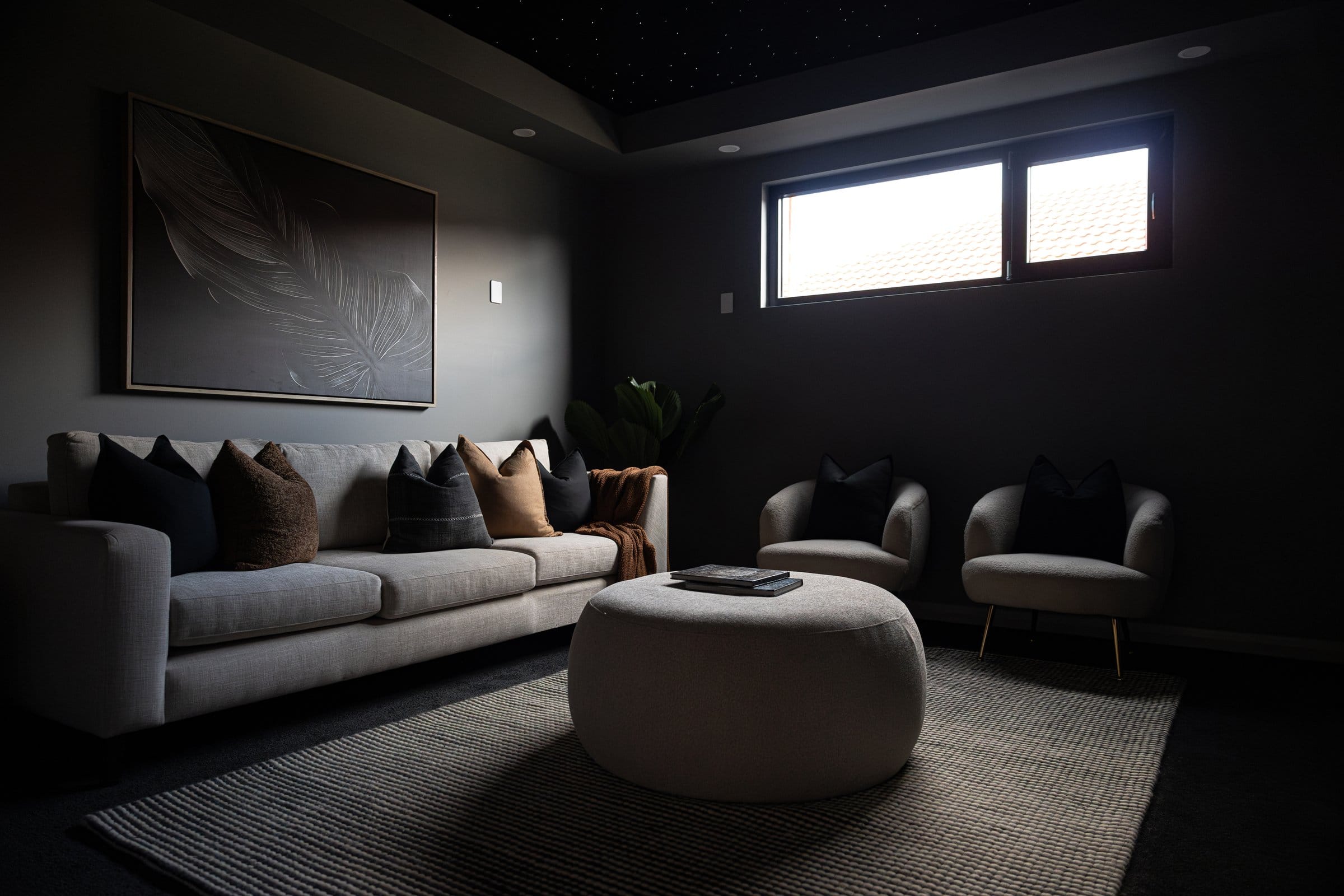 Media room with a star-effect ceiling, a linen sofa and tub chairs in a dark, cinematic palette