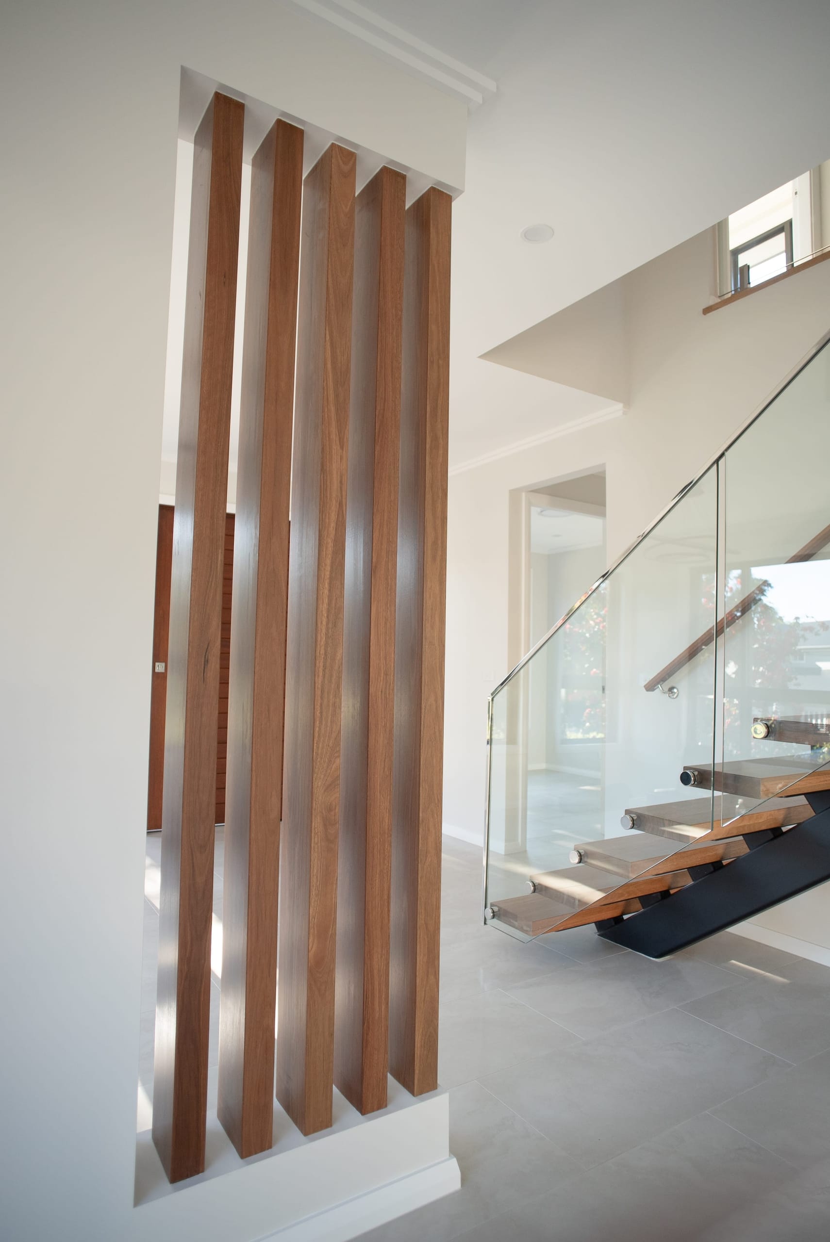Vertical timber blade screen beside the floating staircase and glass balustrade