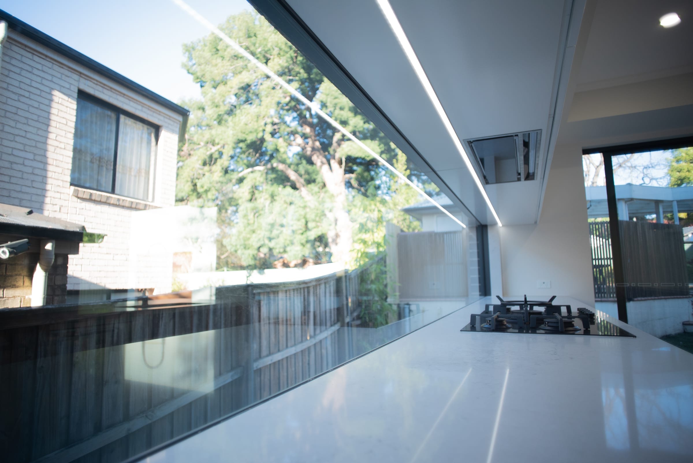 Kitchen detail with a gas cooktop and a full-length window splashback framing a leafy outlook