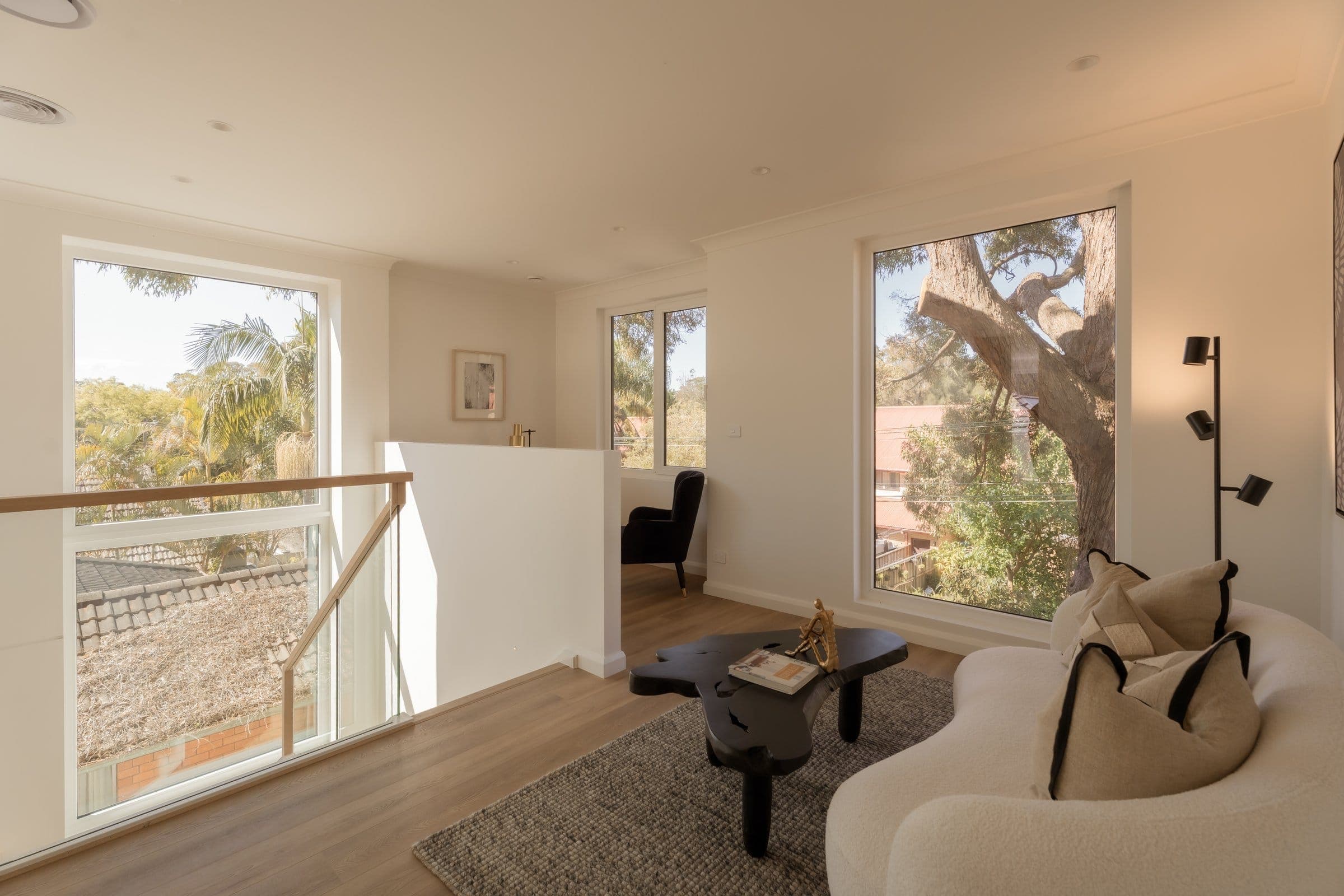 A light-filled, comfortable living room with greenery through large windows inside a Marvel passive house in Lilyfield, Sydney