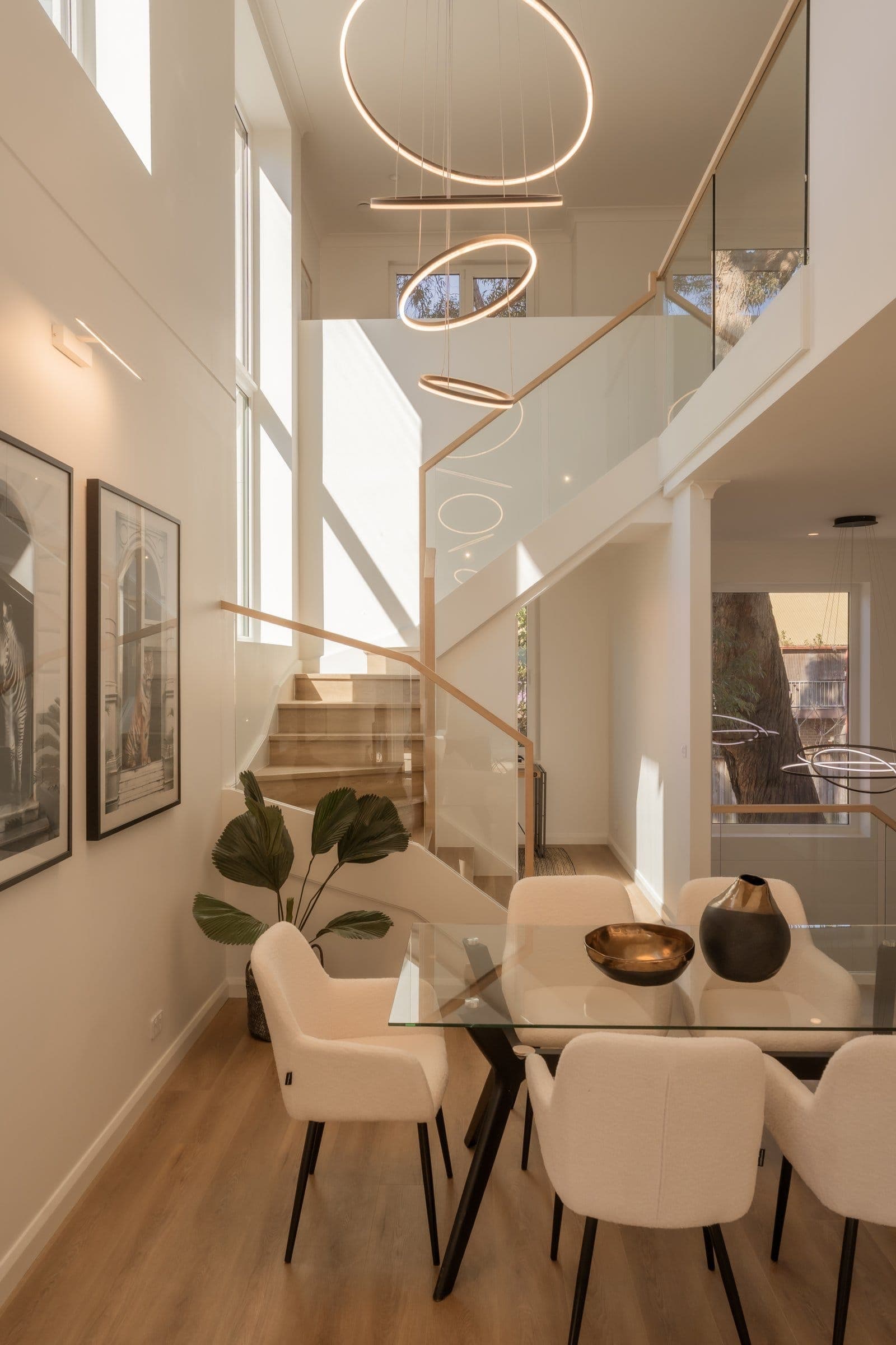 Dining beneath the double-height void and sculptural ring pendant