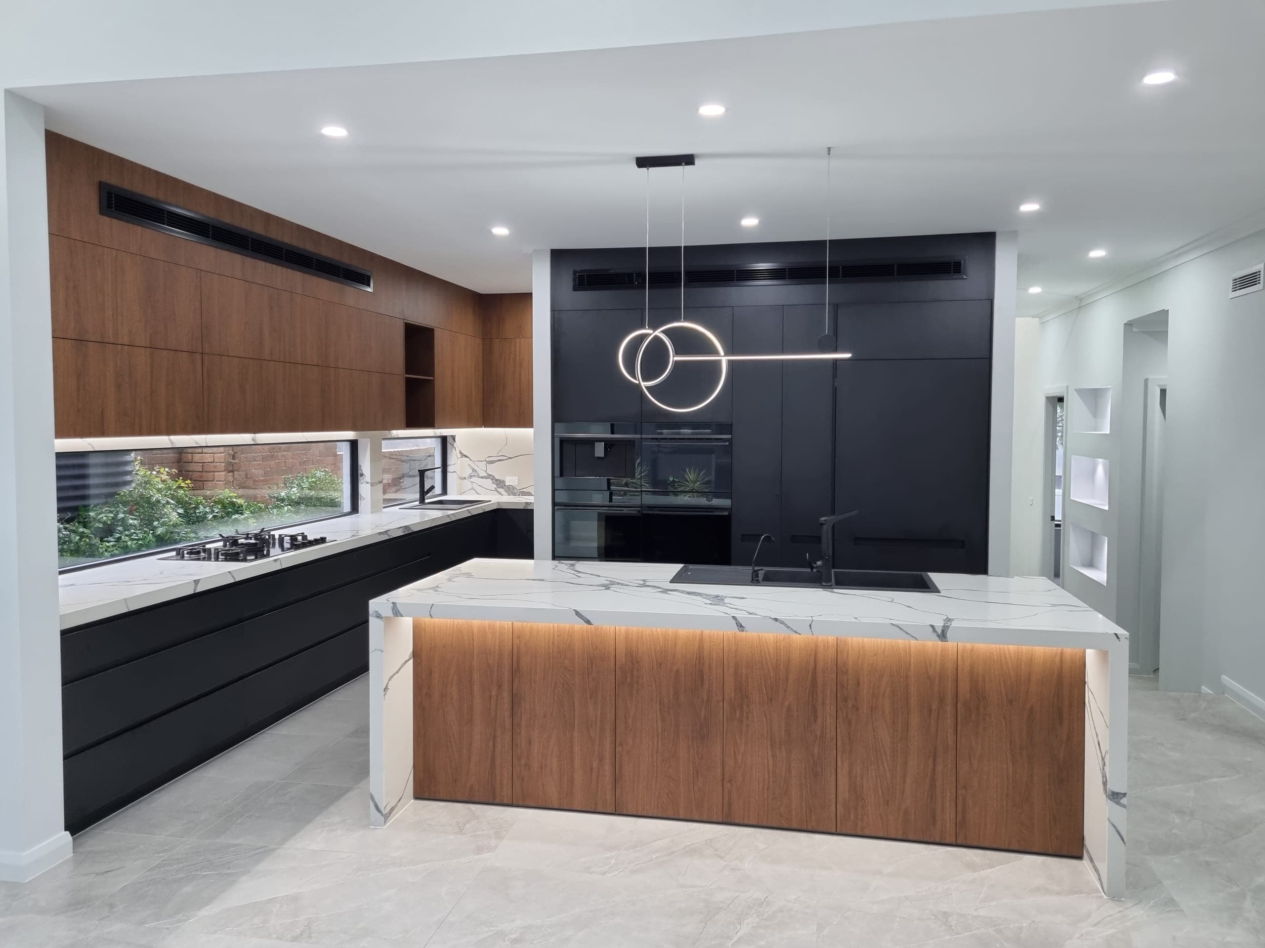 Pennant Hills kitchen with a marble waterfall island, walnut joinery and a sculptural pendant light