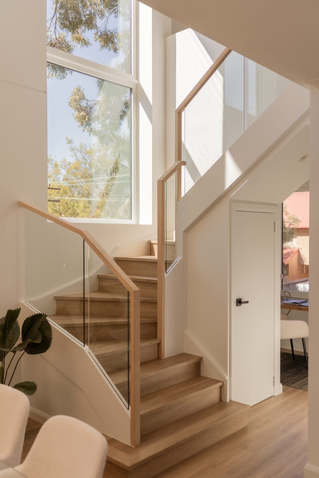 Lilyfield staircase with glass balustrade and a full-height window to the gums