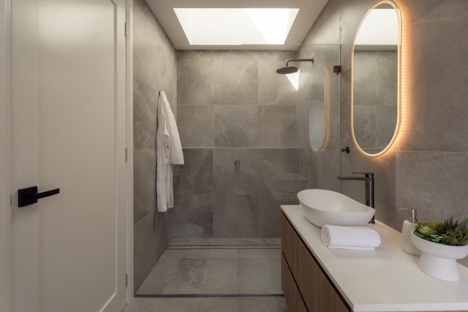 Lilyfield passive house skylit ensuite with stone tiling and walk-in shower